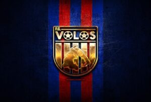 volos fc golden logo super league greece blue metal background football scaled.jpg .pagespeed.ce .I l3h246Qh